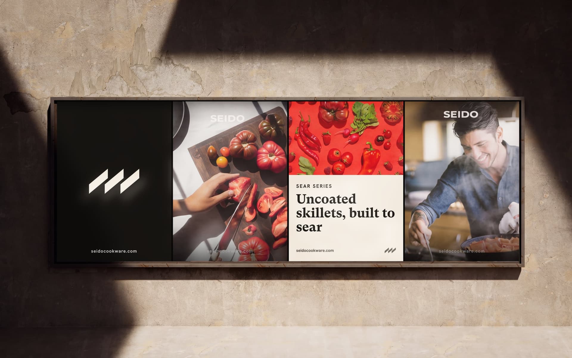 A SEIDO billboard on a sunlit wall: the marque, heirloom tomatoes being sliced, the Sear Series line, and a cook at the stove
