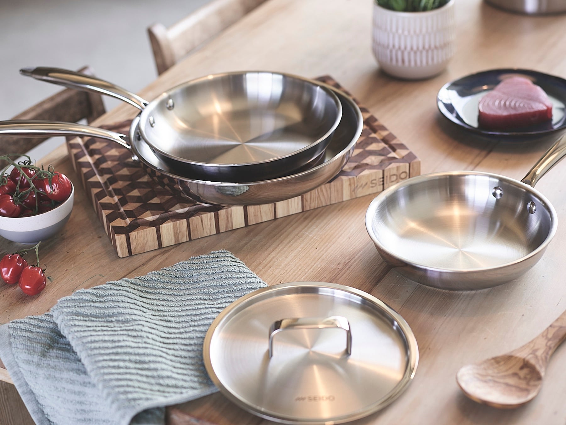 The Sear Series skillet family with a lid on a wooden board