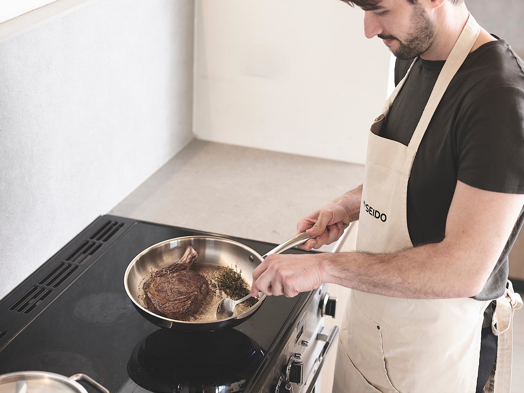 Steak searing in an uncoated stainless steel skillet on the stovetop